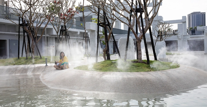 Galerie-Bild 2: Eine Frau und ein Kind sitzen auf einer Insel inmitten eines nebligen Parks mit Bäumen und niedrigem Wasser; Gebäude im Hintergrund.