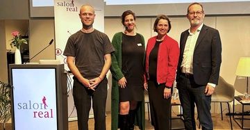 4 Redner (2 Männer, 2 Frauen) auf der Bühne des Salon Real im Rahmen des Clubmeeting, freundlich lächelnd, leger gekleidet