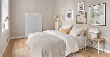 Helles, modern eingerichtetes Schlafzimmer mit Doppelbett, weißer Bettwäsche, Holzboden, Wandbildern und stilvoller Dekoration.
