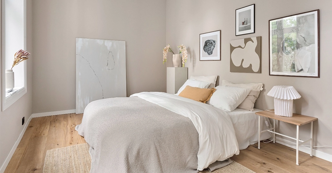 Helles, modern eingerichtetes Schlafzimmer mit Doppelbett, weißer Bettwäsche, Holzboden, Wandbildern und stilvoller Dekoration.