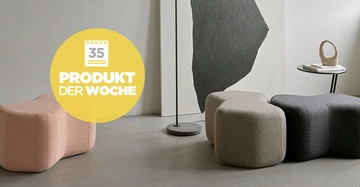 Drei gepolsterte Hocker in verschiedenen Farben stehen nebeneinander in einem modernen Raum neben einem runden Tisch mit Deko. Gelber Kreis mit Text 35 PRODUKT DER WOCHE überlagert Hocker.