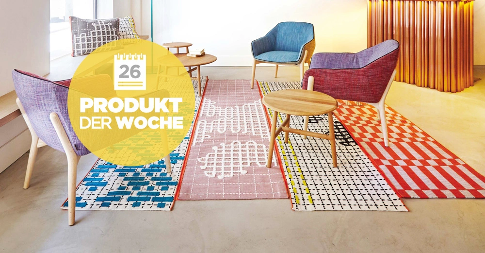Mehrere bunte Sessel und kleine Tische stehen auf gemusterten Teppichen in einem modernen Raum KONTEXT Ein gelber Kreis zeigt Text: 26 PRODUKT DER WOCHE