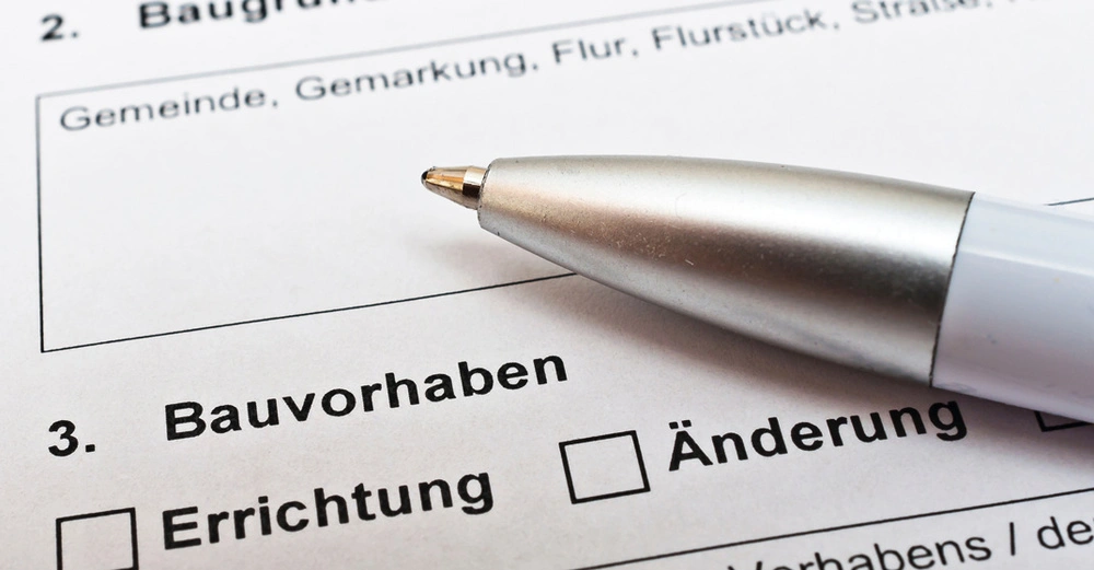 Formular für Baubewilligung liegt auf Tisch, Kugelschreiber darauf. Zu lesen: Bauvorhaben, Errichtung, Änderung