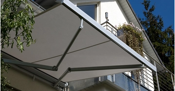 Ausfahrbare Markise spendet Schatten auf einem Balkon eines Einfamilienhauses an einem sonnigen Tag.