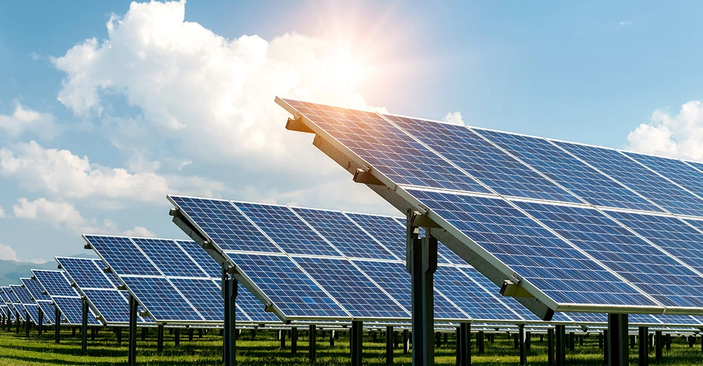 Reihen von Solarmodulen auf einer grünen Wiese unter blauem Himmel mit Sonnenschein, die die von der ASFINAG zur Verfügung gestellten Flächen für Photovoltaikprojekte durch Dritte symbolisieren und zur Energiewende in Österreich beitragen.