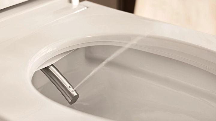 Nahaufnahme Duschfunktion in einem Dusch-WC, dünner Wasserstrahl kommt aus Düse