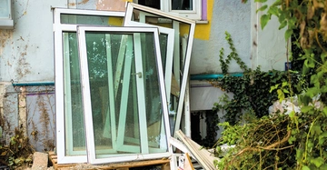 Fenstertausch: fünf alte Kunststofffenster lehnen an Fassade von Altbau, nachdem sie ausgebauit wurden. Rechts im Bild ein Strauch