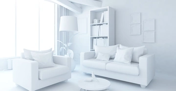 Ein Sessel und ein Sofa stehen nebeneinander in einem hellen, modernen Raum mit großen Fenstern, einem runden Couchtisch, einem Bücherregal und mehreren leeren Rahmen an der Wand.