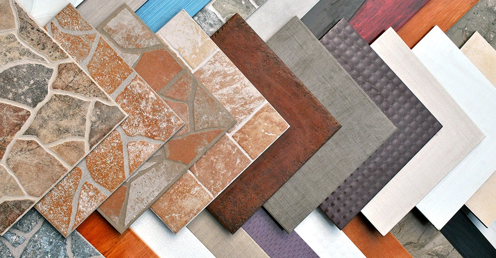 Eine Auswahl an verschiedenen Fliesen in unterschiedlichen Mustern, Farben und Materialien überlappend nebeneinander aufgelegt.