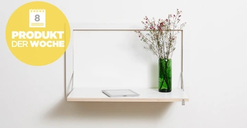 Eine an der Wand befestigte weiße Regalfäche mit einer grünen Vase gefüllt mit Blumen und einem Tablet darauf. Links oben ein gelber Kreis mit der Aufschrift Produkt der Woche und einer Kalendergrafik 8