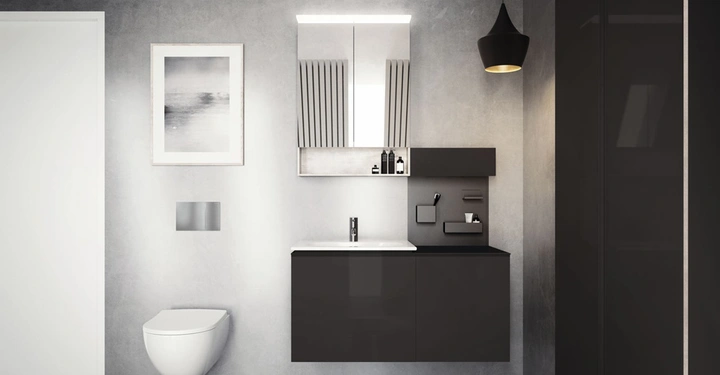 Ein schwarzes Waschbecken mit integriertem Spiegel und Hängelampen an einer grauen Wand im Badezimmer neben einer hängenden Toilette mit einem Kunstwerk daneben.