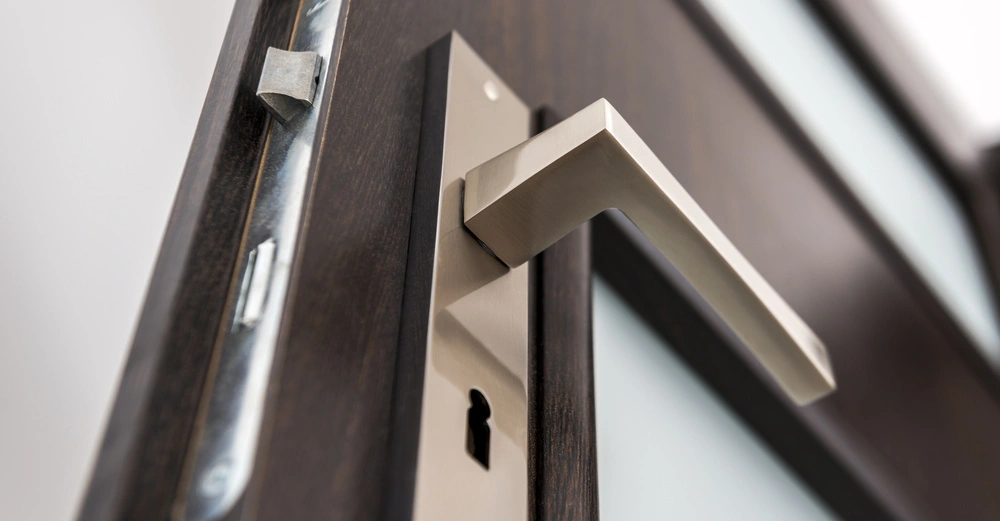 Geöffnete Tür aus dunklem Holz mit mattgoldenem Griff