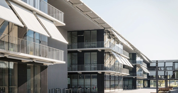 Galerie-Bild 2: Modernes Gebäude mit Balkonen und ausgefahrenen Markisen-stehend in einem sonnigen Innenhof mit Bänken und Bäumen im Hintergrund