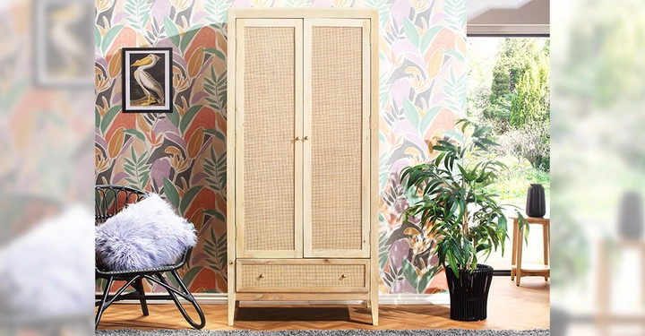 Galerie-Bild 9: Zweitüriger Schrank von Desser & Co mit Rattanfronten und goldenen Griffen, dahinter eine botantische Tapete in Grün, Gelb, Hellrot, Lila und Anthrazit