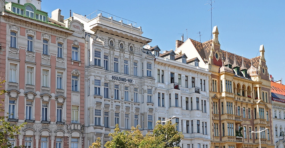 Historische Häuserfassaden in Wien mit prachtvollen Stuckverzierungen und stilvollen Jugendstil-Elementen bei strahlend blauem Himmel.