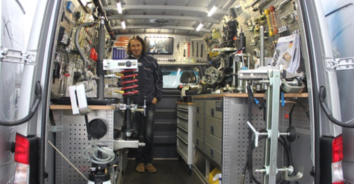 Galerie-Bild 14: Ein Mann steht in einem gut ausgestatteten, von innen beleuchteten Werkstattwagen und ist umgeben von Werkzeugen, Maschinen und Zubehör, die ordentlich an den Wänden und auf den Arbeitsflächen angebracht sind.