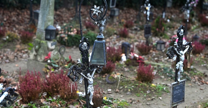 Schmiedeeiserne Grabkreuze und Laternen auf einem düsteren Wiener Friedhof, passend zum Friedhof der Namenlosen.