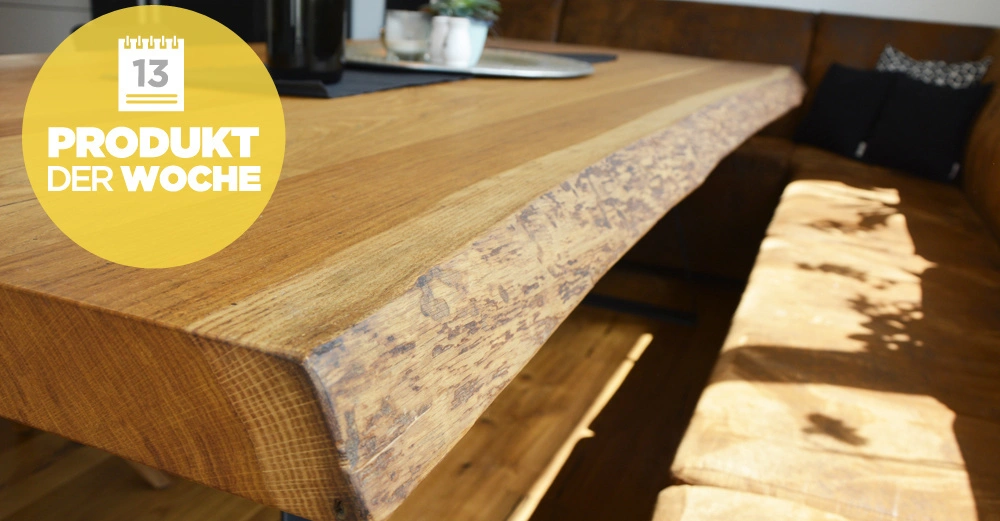 Holztisch steht in einer modernen Küche auf einem Holzboden zwischen zwei Sitzbänken. Gelber Kreis mit Text 13 PRODUKT DER WOCHE in der oberen linken Ecke.