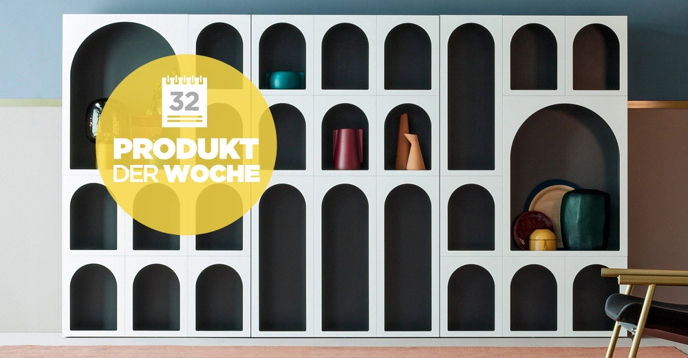 Regaleinheit zeigt dekorative Gegenstände Sitzmöbel im Vordergrund Gelber Kreis mit Text 32 PRODUKT DER WOCHE Wohnungseinrichtung modern gestaltet wandmontiert klar strukturiert helle und dunkle Farben verwendet