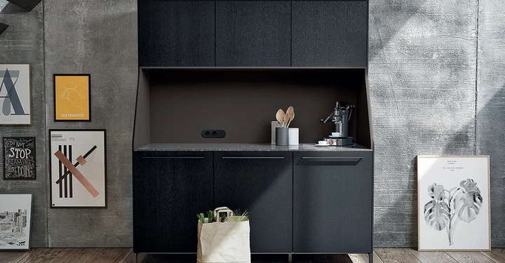 Galerie-Bild 1: Schwarzer Schrank steht an einer Betonwand in einer modernen Küche. Auf dem Schrank stehen Küchenutensilien und eine Maschine. Daneben hängt Kunst auf der Wand. Eine Papiertüte steht auf dem Holzboden. Zu lesende Texte: San Francisco DO NOT STOP DREAMING BUT KEEP DOING