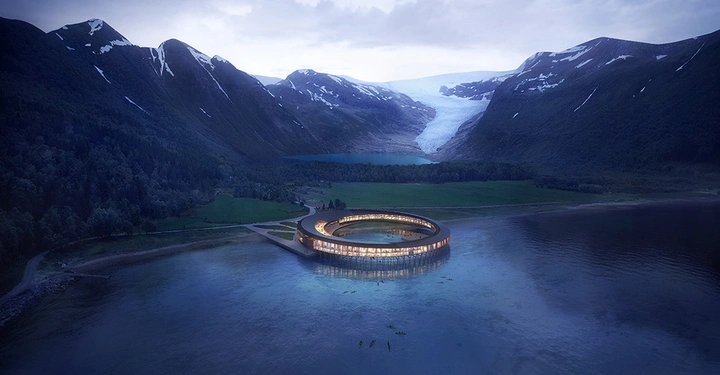Galerie-Bild 3: Rundes Gebäude leuchtet am Ufer eines Sees umgeben von hohen Bergen und Gletschern in der Dämmerung.