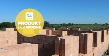 Mauerblöcke in verschiedenen Größen formen die Struktur eines Rohbaus im Freien umgeben von grünen Feldern und Bäumen Kalender-Bild mit der Nummer 34 und Text PRODUKT DER WOCHE