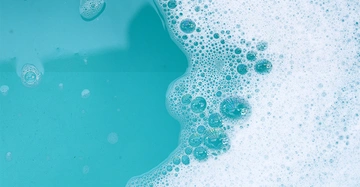 Ein Becken mit türkisem Badewasser, auf dem Seifenschaub treibt.