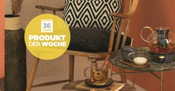 Holzstuhl mit schwarz-weißem Kissen Tee-Set auf kleinem Tisch gemütliche Ecke mit Pflanze und oranger Wand Text: 36 Produkt der Woche