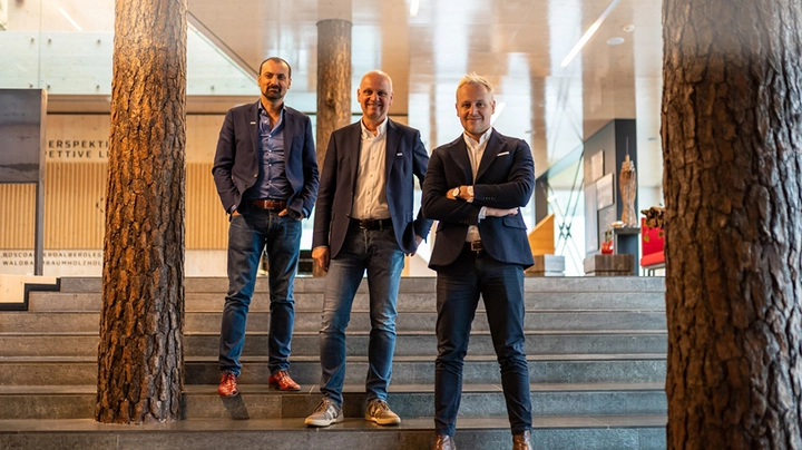 Galerie-Bild 2: Drei Männer in Jeans und Sakkos leger-modern stehen auf einer großen steinernen Treppe in einem Firmengebäude.