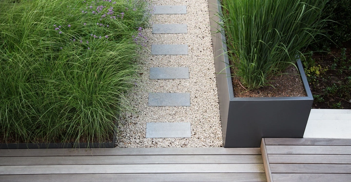 Steinplatten Bilden Pfad Zwischen Hohem Gras Leitend Zu Holzterrasse In Modernem Garten Setting