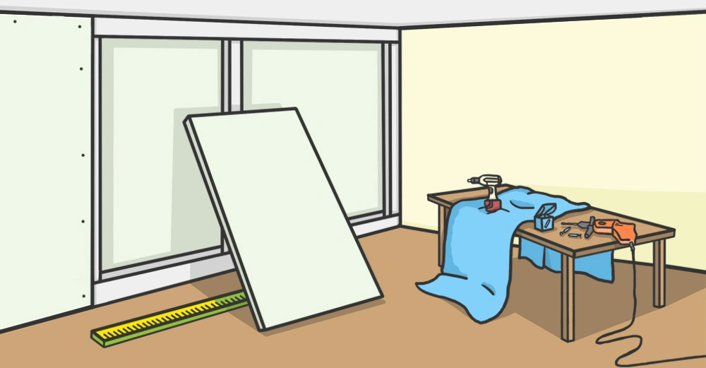 Eine große Platte lehnt in einem Raum an einer Wand bei Fenstern ein Maßstab liegt am Boden ein Arbeitstisch ist bedeckt mit Werkzeugen Stoff und einer Bohrmaschine.