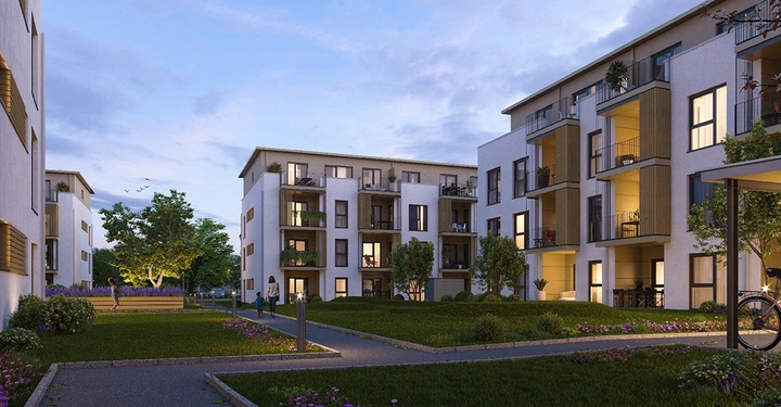 Mehrfamilienhäuser stehen beleuchtet im Dämmerlicht Menschen spazieren im Innenhof mit gepflegten Grünflächen und Bäumen im Hintergrund sind weitere Gebäude und ein klarer Himmel zu sehen.