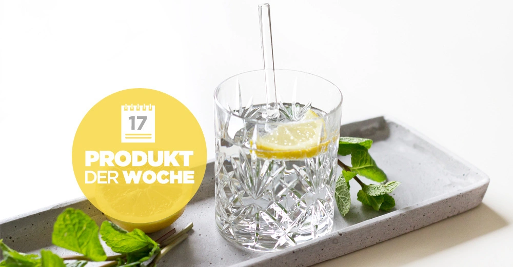 Kristallglas Wasser mit Zitronenscheibe und Strohhalm steht auf einem Tablett umgeben von frischen Minzblättern gelber Kreis mit Text 17 Produkt der Woche links daneben
