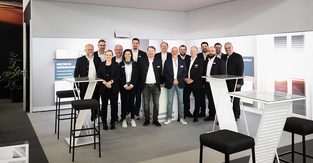 Das Team von Vogel&Noot im Messestand des Unternehmens lächelt in die Kamera.