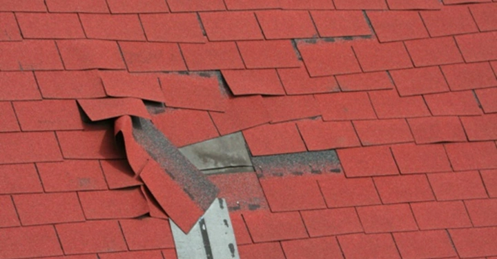 Galerie-Bild 4: Rote Dachschindeln sind teilweise angehoben und beschädigt in einem Schrägdachbereich vermutlich durch Wind oder Sturm in einem Wohngebiet.