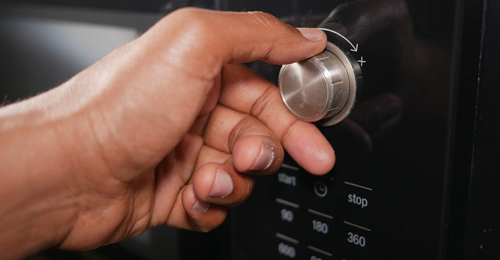 Eine Person nimmt Einstellungen an ihrer modernen Mikrowelle mit vielen verschiedenen Funktionen vor.