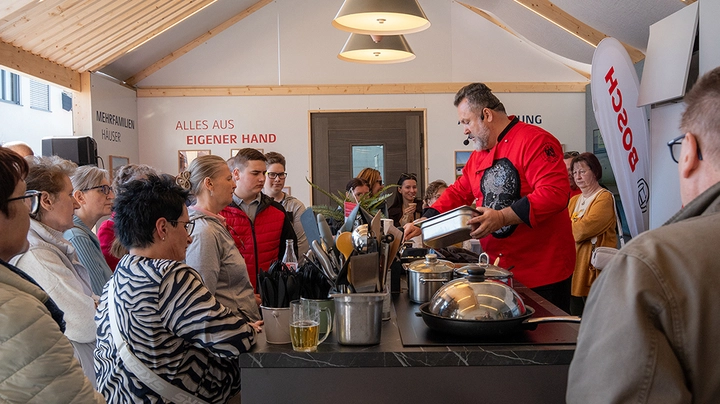 Koch arbeitet vor interessiertem Publikum und brät gerade etwas an