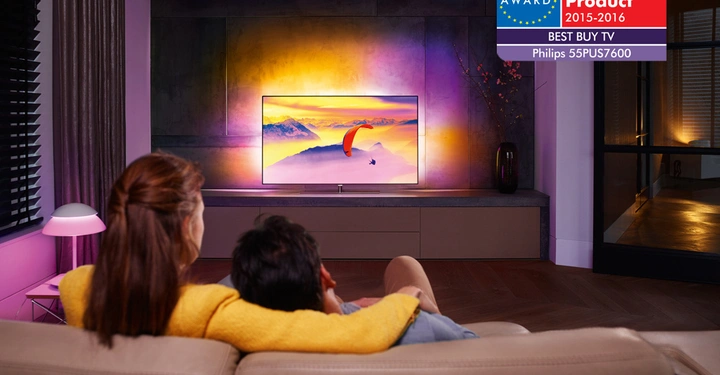 Galerie-Bild 5: Paar sitzt auf Sofa Fernseher schauen Wohnzimmer abends EISA Award Best Product 2015-2016 Best Buy TV Philips 55PUS7600 Text auf dem Fernseher farbenfrohe Natur Landschaft.