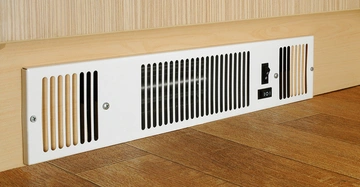 Ein weißes Lüftungsgitter ist an einer hellen Holzwand befestigt in einem Raum mit holzfarbenem Boden. Es hat Lüftungsschlitze und einen Schalter mit den Positionen I O I.