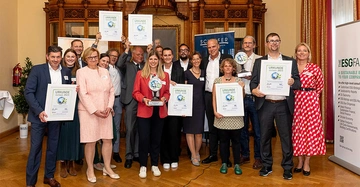 Die Gewinner des CTC-Awards 2023 mit Zertifikaten fröhlich auf einer Bühne vereint, zu sehen sind 18 Menschen in Businessoutfit, davon 8 Frauen