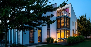 Modernes Haus beleuchtet Abend Bäume Blumen umgeben