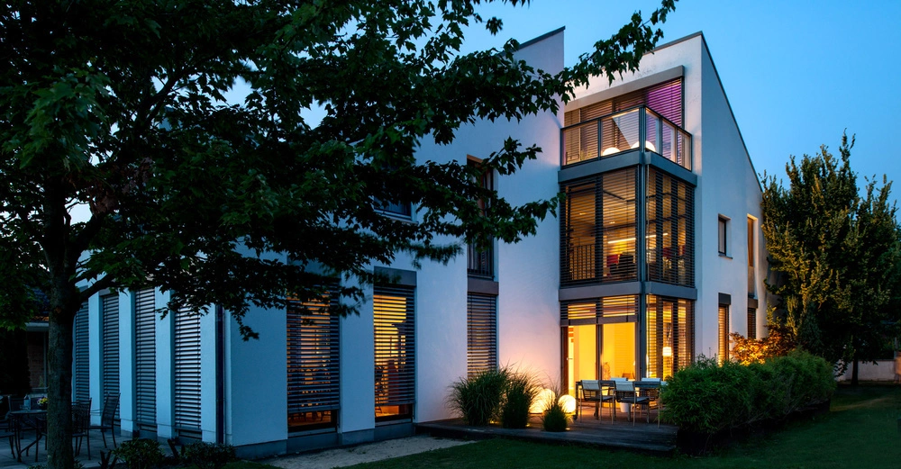 Modernes Haus beleuchtet Abend Bäume Blumen umgeben