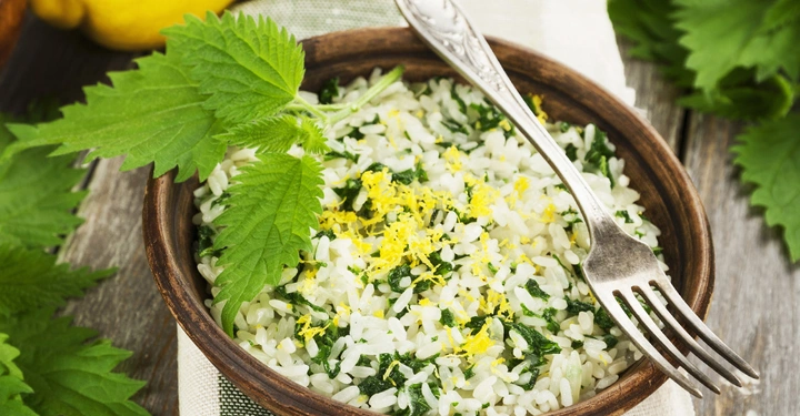 Holzschale enthält Reis mit gehacktem Gemüse und Zitronenschale garniert Gabel liegt daneben Umgebung zeigt grüne Blätter und gelbe Zitronen auf einem Holztisch