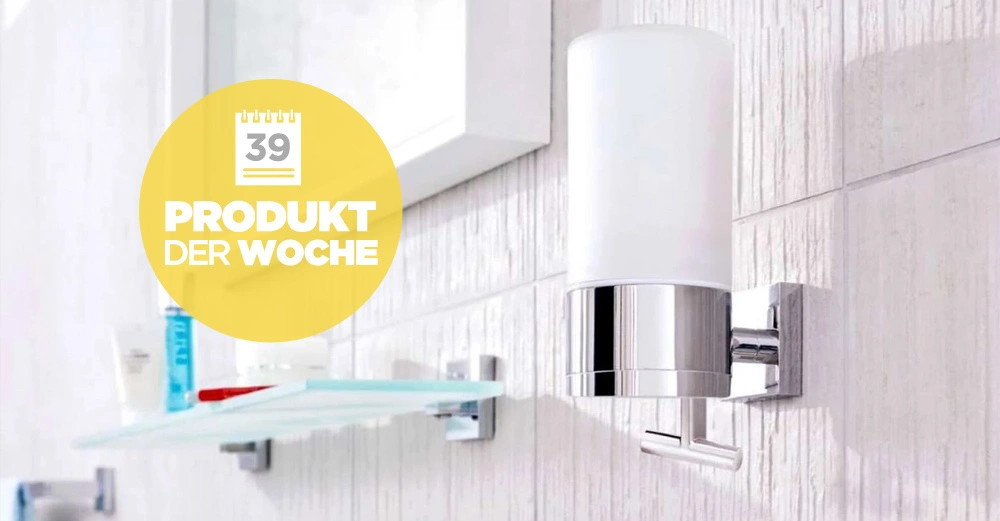 Seifenspender an der Wand in einem Badezimmer mit hellen Fliesen montiert Text 39 Produkt der Woche Blurry Regale und Pflegeprodukte im Hintergrund