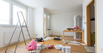 Leiter stehend Renovierungsarbeiten Wohnung verstreut Werkzeug Papier Malerutensilien Holztisch Kartonboden große Fenster Holzfußboden Abdeckungen Heizkörper.