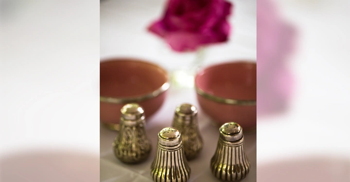 Galerie-Bild 5: Vier silberne Salz- und Pfefferstreuer stehen auf einem weißen Tischtuch In der Nähe befinden sich zwei rosa Schalen und eine unscharfe rosa Blume im Hintergrund