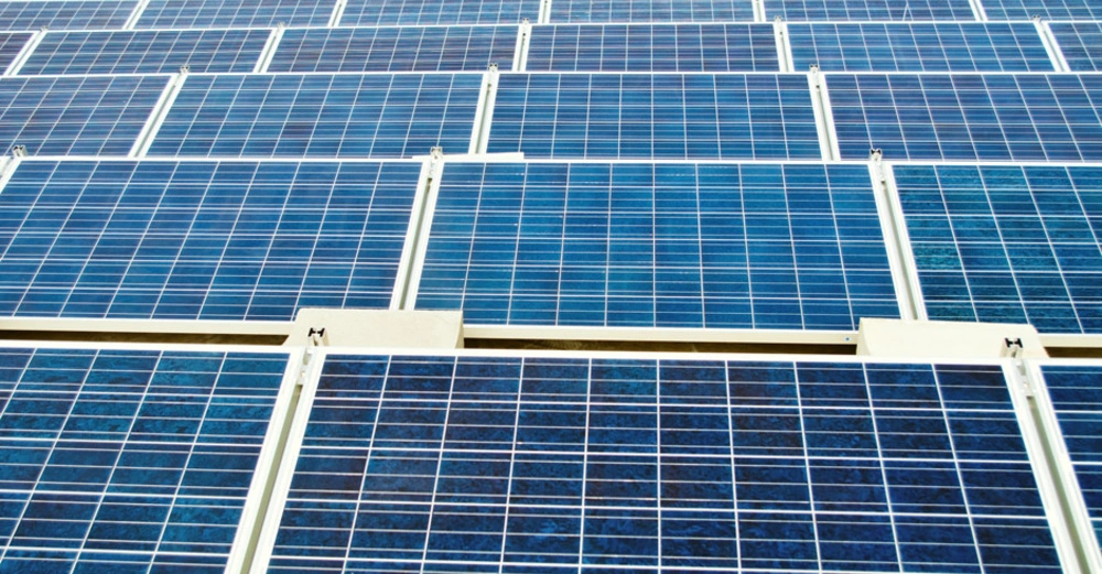 Mehrere Reihen von blauen Solarpaneelen stehen draußen auf einem großen Feld die Sonnenenergie absorbieren um Strom zu erzeugen.