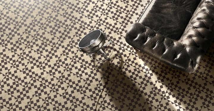 Galerie-Bild 1: Sofa und Stehlampe liegen auf einem Boden mit geometrischen schwarz-weißen Mustern.