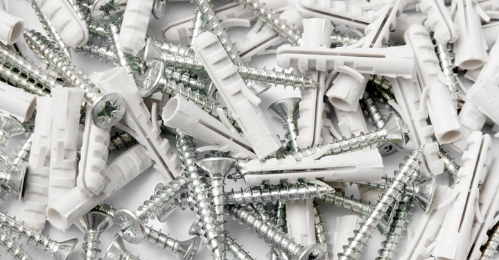 großer Haufen mit Schrauben und weißen Kunststoffdübeln