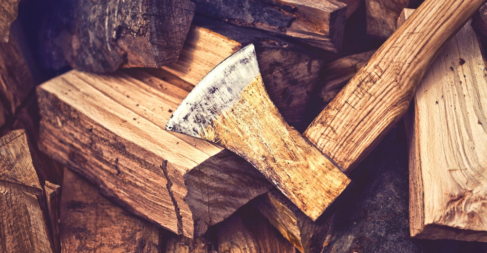 Axt liegt auf gehacktem Brennholz in einem Stapel Holzstücken in einem rustikalen Umfeld